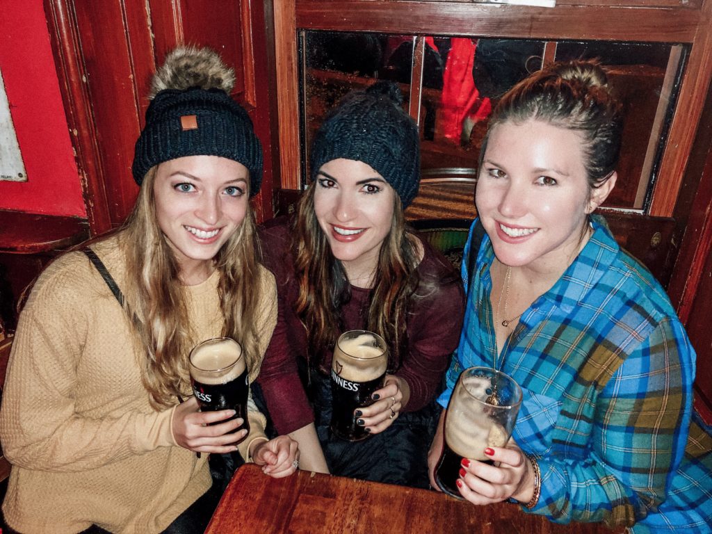 three girls drinking Guinness at a pub in ireland