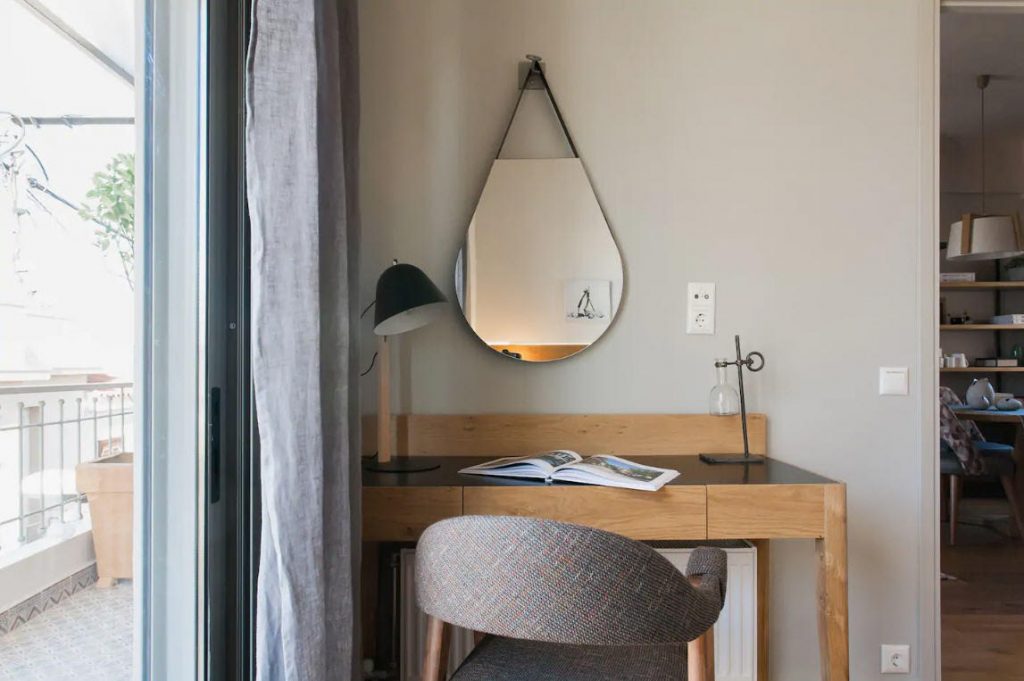 cute desk and chair with mirror hanging and sliding doors out to balcony inside The Cutest Airbnb Vacation Rental In Athens, Greece