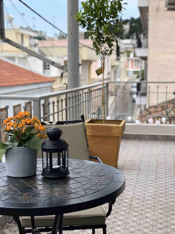 beautiful balcony The Cutest Airbnb Vacation Rental In Athens, Greece overlooking Thission neighborhood with outdoor bistro table and flowers