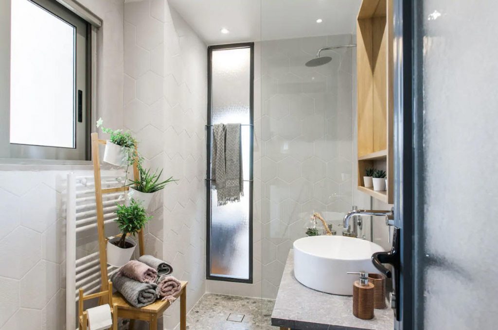 bathroom in beautiful Airbnb Vacation Rental In Athens, Greece with plants and fresh towels, walk in shower and sink view