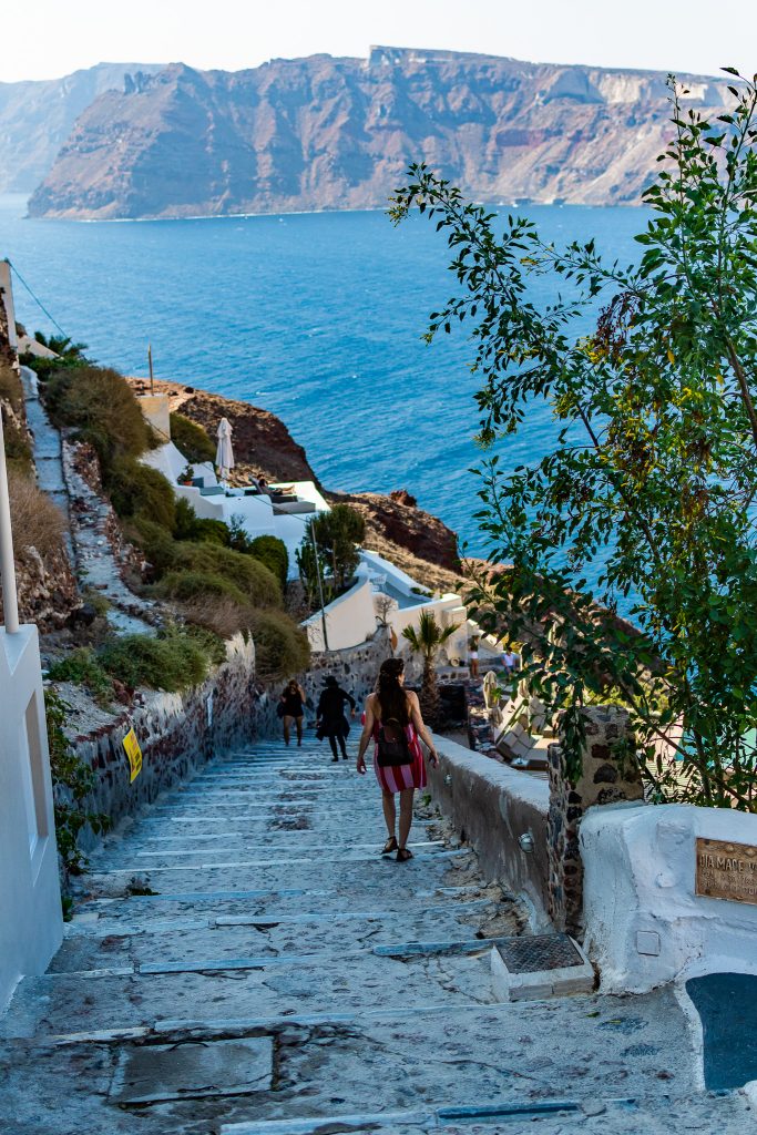 girl walking down the steps to to ammoudi bay in oia santorini greece