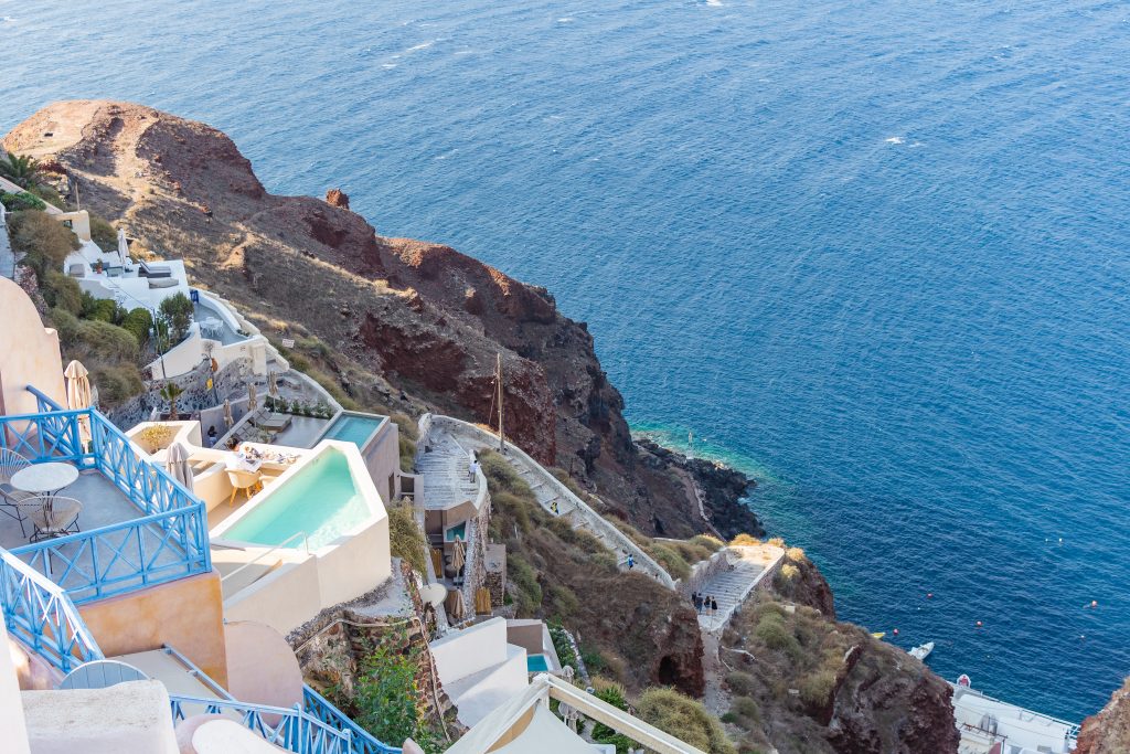 view of stairways and steps leading down to ammoudi bay in oia santorini greece with view of the Aegean in the background