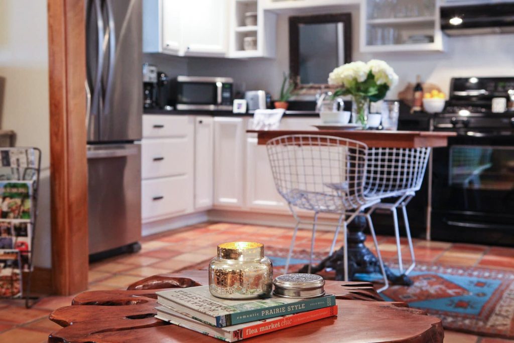 kitchen and table in emma haus fredericksburg with moroccan rug and extra chairs for seating, charming kitchen in emma haus fredericksburg cottage rental in texas hill country, coffee table books and decor in emma haus fredericksburg