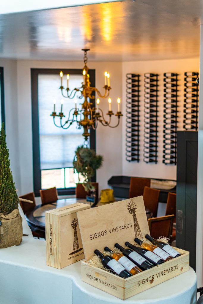 Wooden box of wines inside Signor Vineyards winery in Fredericksburg, TX with chandelier and dining table hanging in the background