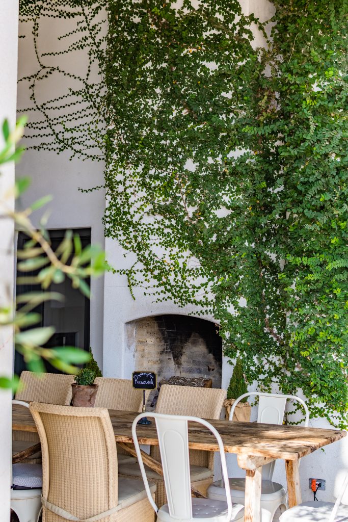 outdoor table and chairs with reserved sign and ivory covered chimney at signor vineyards winery in fredericksburg, texas