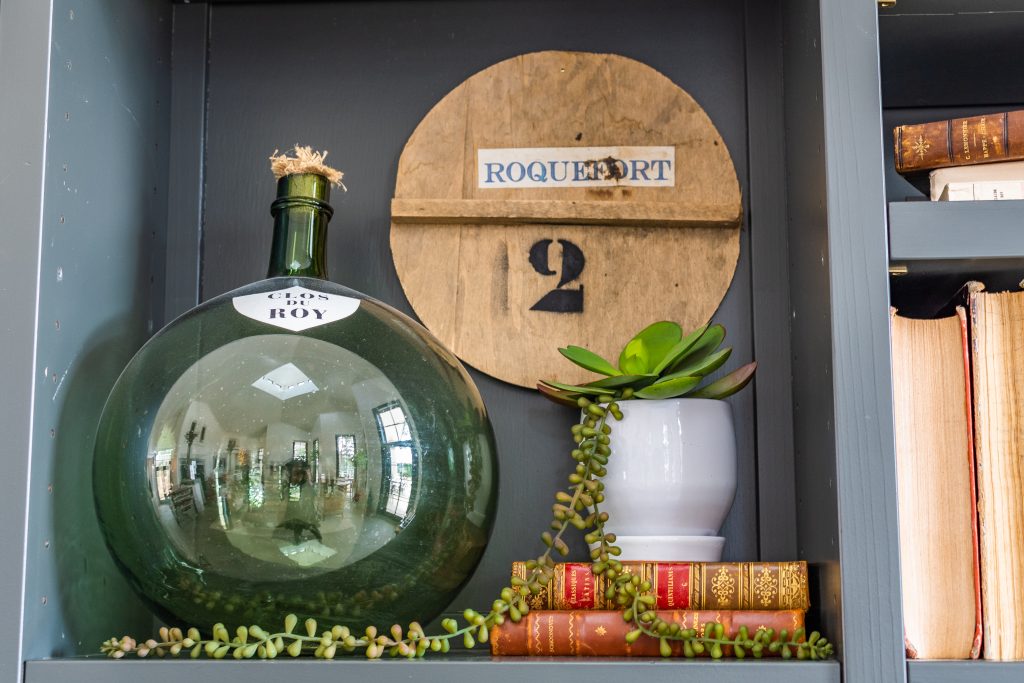 green demijohn bottle and succulent plant on top of books