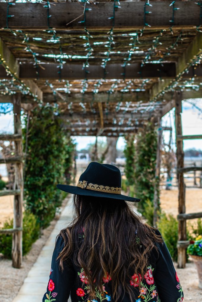 landry has landed, landry braud, girl with long brown hair and black hat walking towards joanna's market in signor vineyards winery in fredericksburg texas