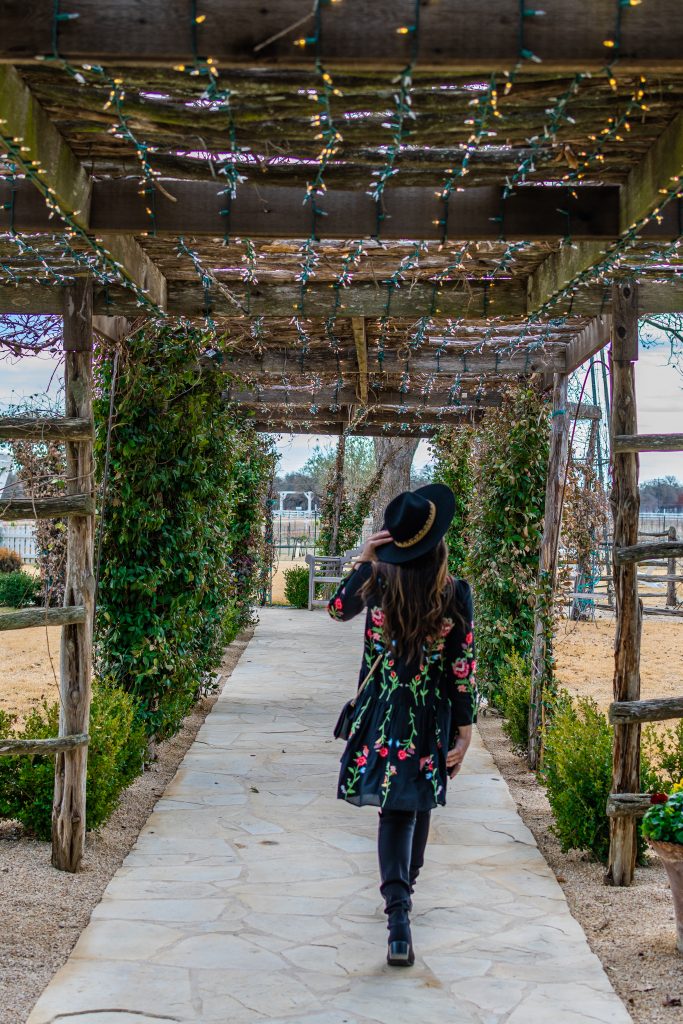 landry has landed, landry braud, girl with long brown hair and black hat walking towards joanna's market in signor vineyards winery in fredericksburg texas