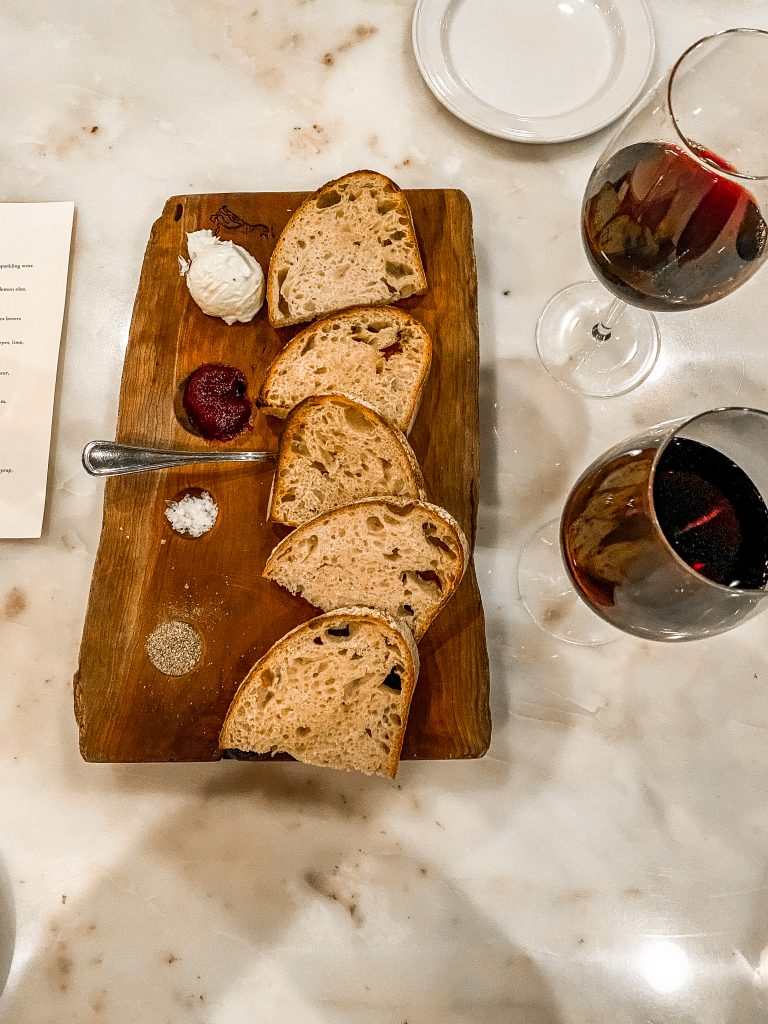 brot and butter appetizer and ott's german bistro in fredericksburg texas, fresh bread with salt, pepper, fresh jams and butter with 2 red wine glasses to accompany it, best restaurants in fredericksburg