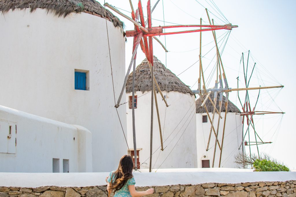 best things to do in mykonos, greece, visit the iconic windmills, girl exploring windmills in mykonos greece