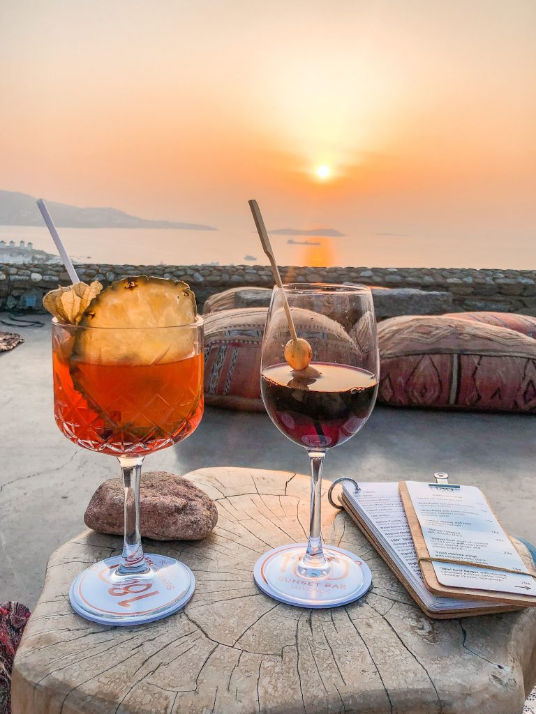 drinks and sunset view from 180° Sunset Bar in Mykonos Greece overlooking Mykonos Town and the windmills. Where to watch the sunset in mykonos, the best things to do in mykonos greece