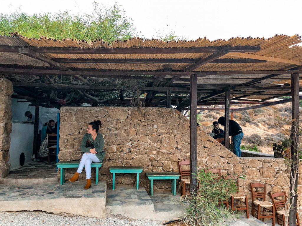 kiki's tavern mykonos, kiki's tavern restaurant agios sostis beach, best restaurants in mykonos, best things to do in mykonos, local cuisine mykonos, view of beach shack with girl waiting in line to eat at the restaurant